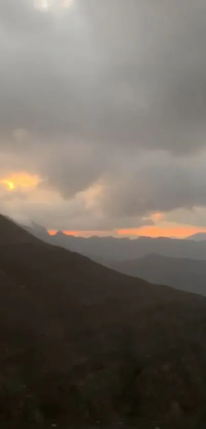 Moody mountain sunset with clouds and glowing horizon, perfect for mobile wallpaper.