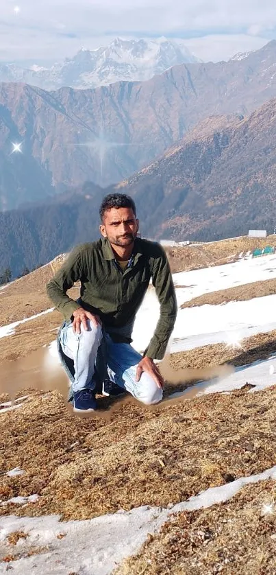 Man in green shirt on snowy mountain with sparkling sky.