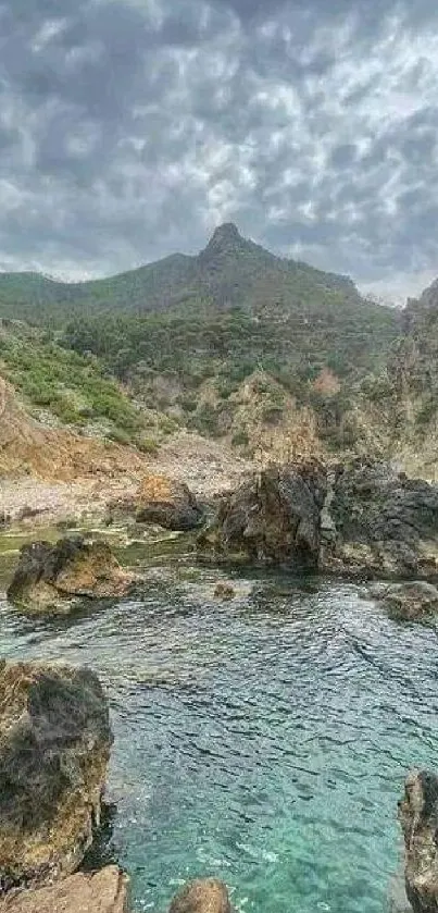 Mountainous coastal scene with rocky shore and cloudy sky.