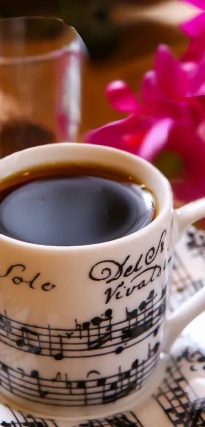 Coffee cup with musical notes beside pink flowers.