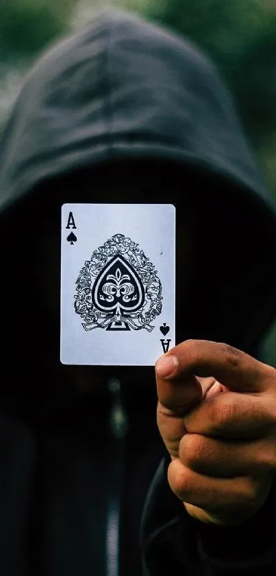 Hooded figure holding Ace of Spades card.