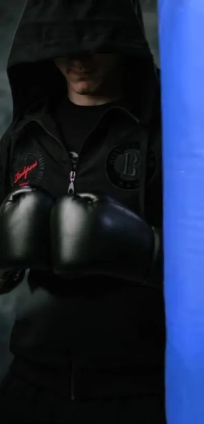 Boxer in black hoodie facing blue punching bag.