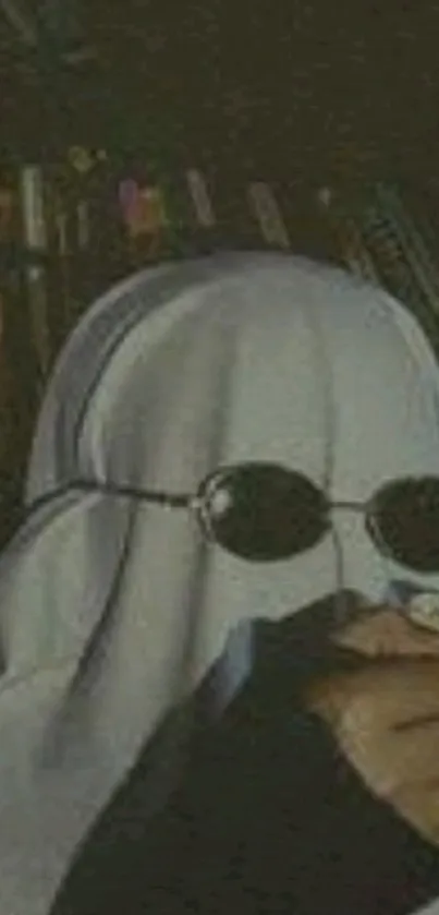 Cloaked figure wearing sunglasses against dark background.