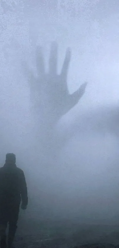 Mysterious hand silhouette in a foggy scenery, creating an eerie mobile wallpaper.