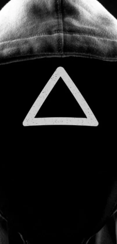 Mysterious black hooded figure with triangle symbol on black background.