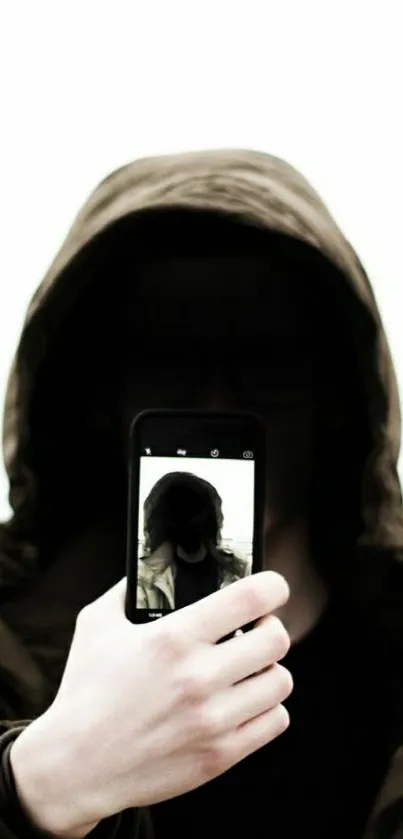 Mysterious hooded figure taking a selfie with a smartphone.