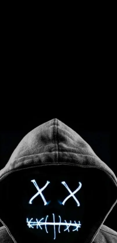 Mysterious figure with glowing neon mask in a dark hoodie, on black background.