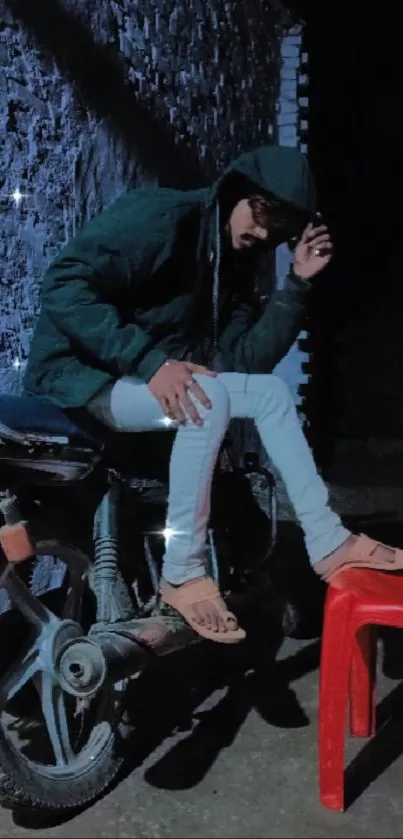 Person sitting on motorcycle at night, exuding a mysterious vibe in a dark setting.