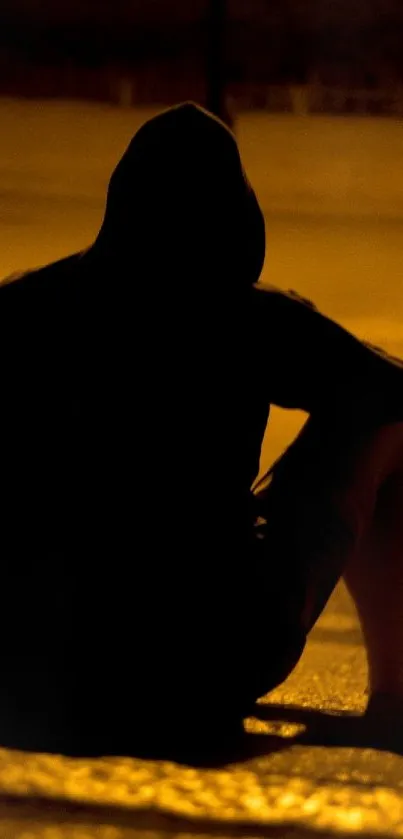 Silhouette of a person sitting on steps at night with amber street lighting.