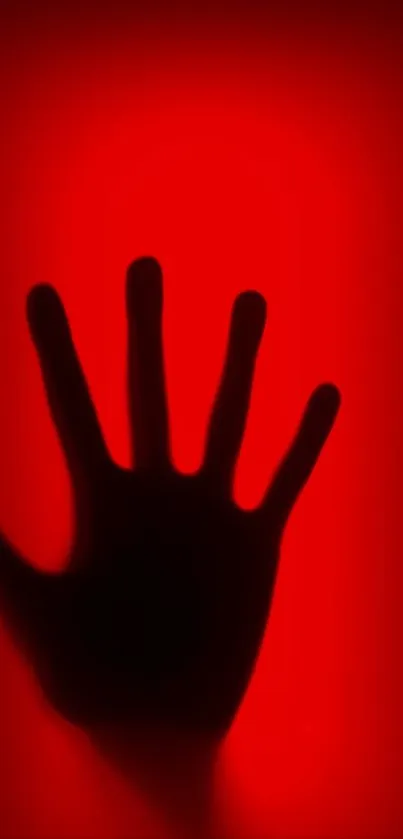 Silhouette of a hand against a vibrant red background.