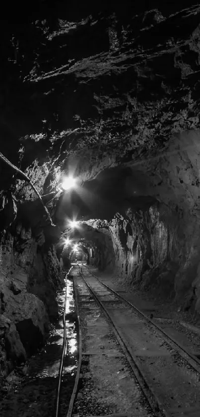 Black and white underground tunnel with railway tracks.