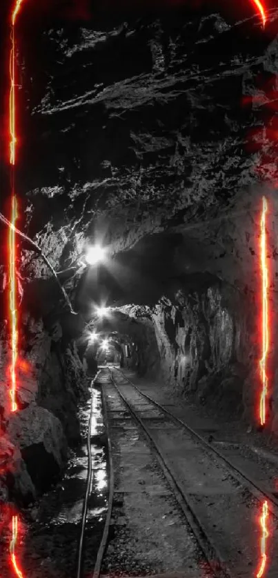 Black and white underground tunnel with rail tracks and rocky walls.