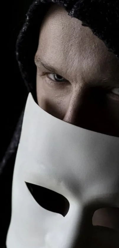 Mysterious figure holding a white mask with a dark background.