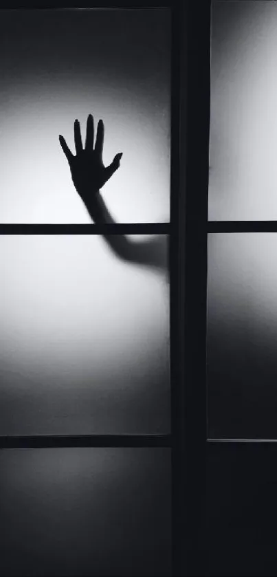 Silhouette of a hand behind frosted glass, creating a mysterious ambiance.