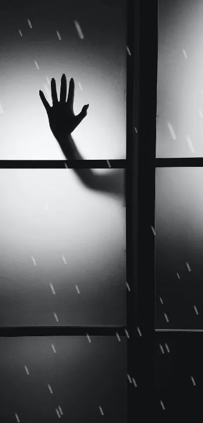 Silhouette of a hand on foggy window in black and white.