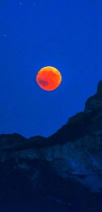 Orange moon over mountain in blue night sky wallpaper.