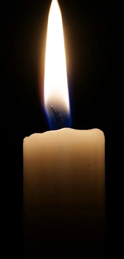 Candle flame glowing in the dark, ideal as a mobile wallpaper.