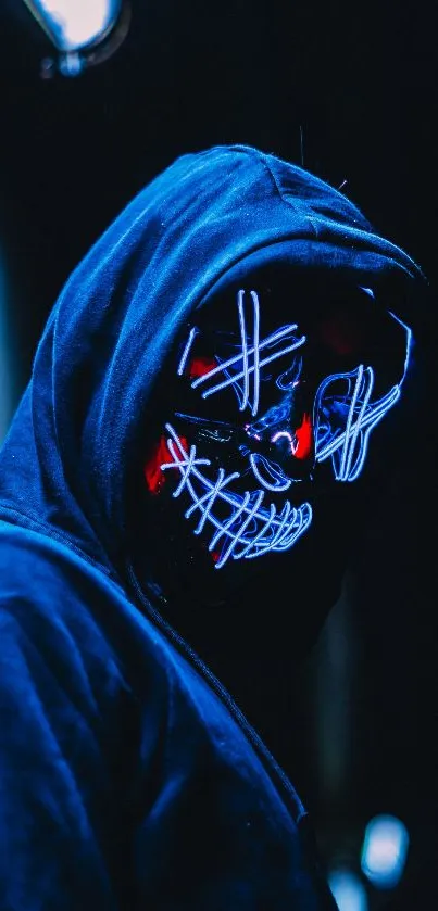 Hooded figure with neon mask in low light setting.