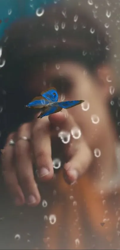 Blue butterfly gently touching a finger through raindrops on glass.