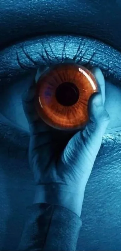 A mystical blue eye being held delicately by hand, with a vivid orange center.