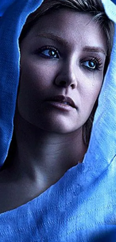 Serene portrait of a woman in blue hood under soft lighting.