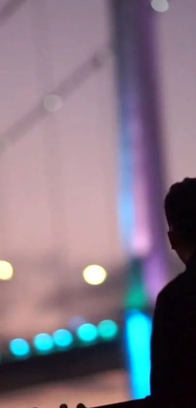 Silhouette of a figure against a softly lit bridge at night.