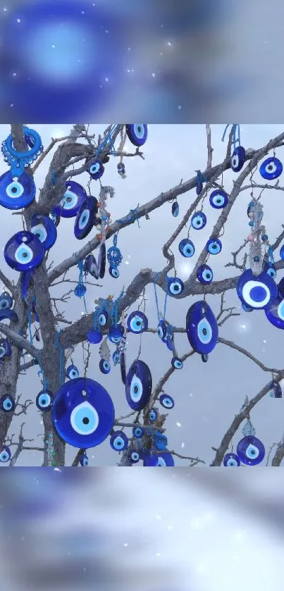 Blue evil eye charms hanging from branches against a serene sky.