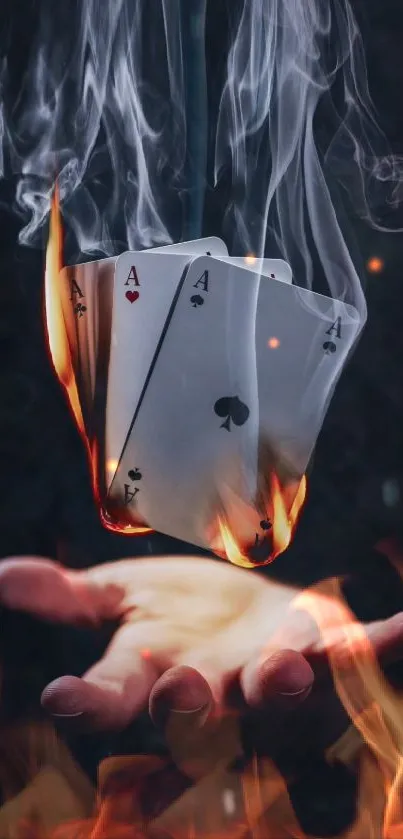 A hand holding flaming, smoking playing cards.