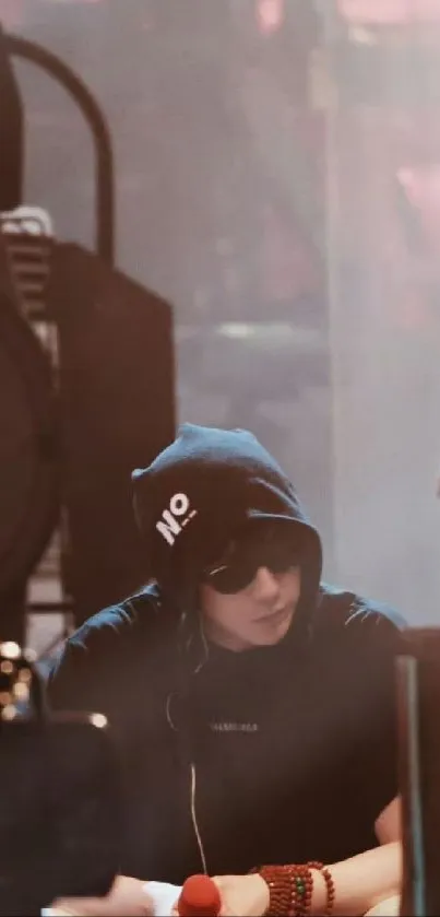 Person in dark hoodie and sunglasses on stage.