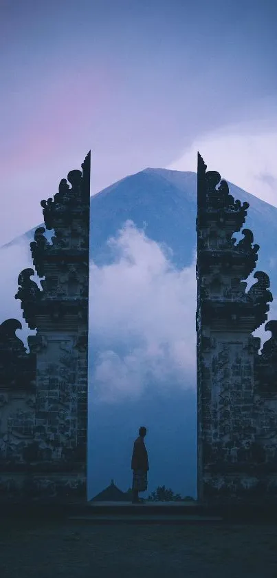 Silhouetted gateway with mountain backdrop in blue misty morning light.