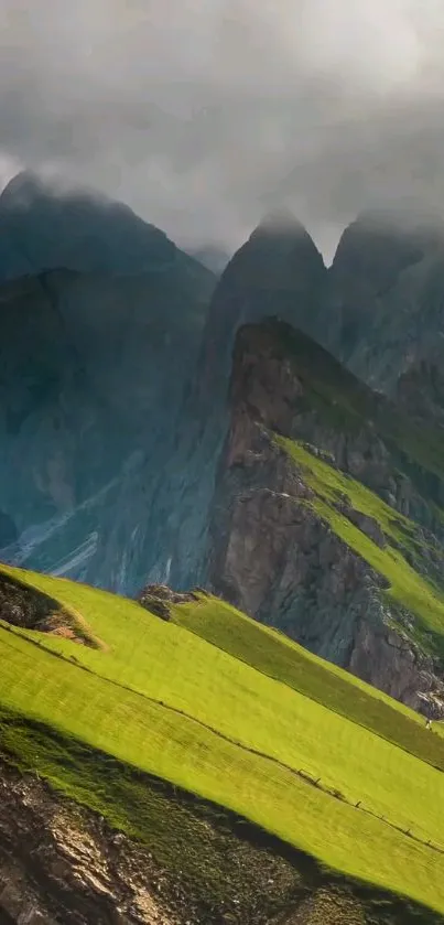 Green hills against dramatic mountain peaks and misty sky.