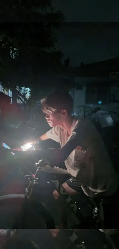 Cyclist illuminated by phone light during nighttime ride.