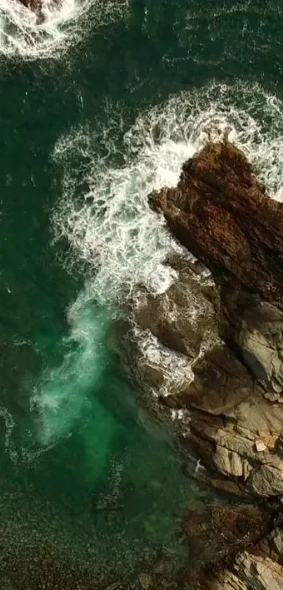 Emerald ocean waves crash against rocky coastline in nature wallpaper.