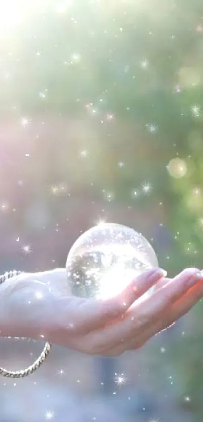 Hand holding a sparkling sphere in ethereal light with green bokeh background.