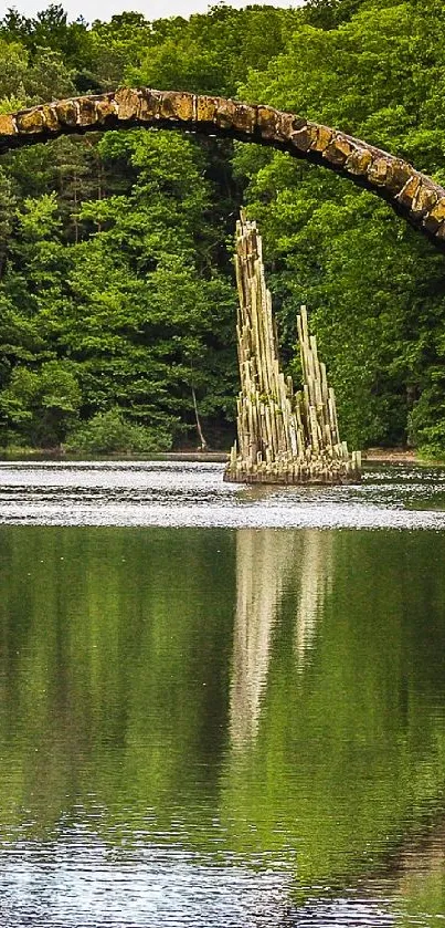 Stone bridge over a reflective river in a lush green forest landscape.