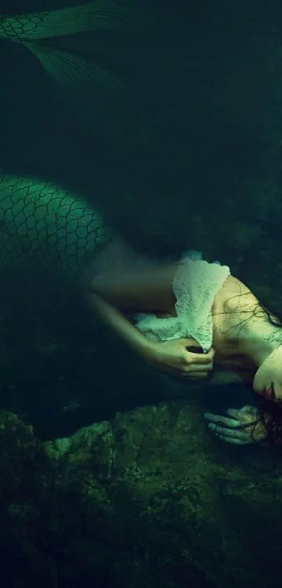 Mystical mermaid rests underwater in dark, serene ocean scene.