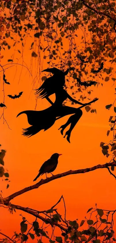 Silhouette of a witch flying against an orange sunset with bats and leaves.