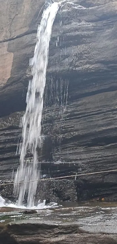 Waterfall flowing over rugged rocks, ideal for mobile wallpaper.