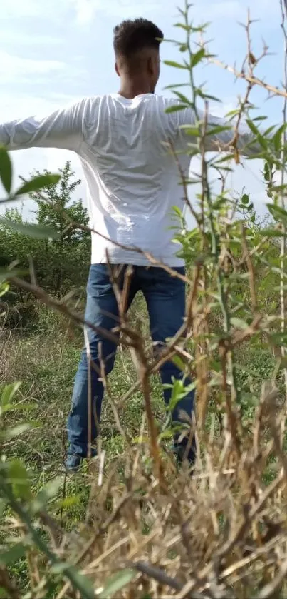 Person in white shirt enjoying nature outdoors with green surroundings.