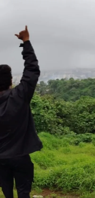 Person pointing at the misty horizon with greenery around.