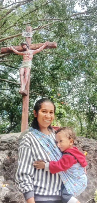 Mother with child in nature, under a crucifix.