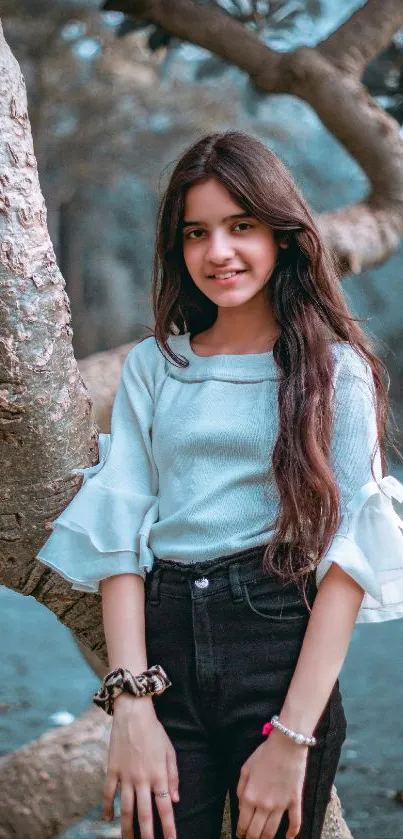 Mobile wallpaper featuring a young girl posing by a tree in a teal autumn setting.