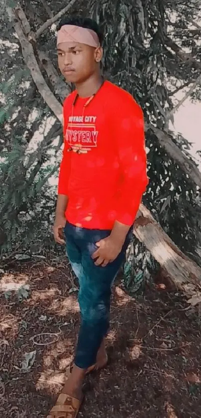 Person in red shirt standing in a forest setting with green foliage.