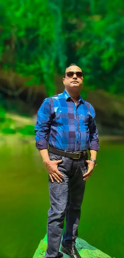 Man in blue shirt standing amidst lush green nature setting.