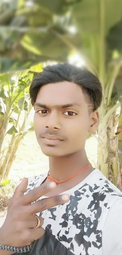 Man posing outdoors by green banana trees, creating a nature-inspired wallpaper.