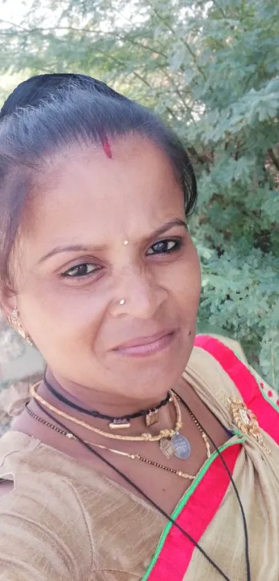 Woman in traditional attire with green leafy background.