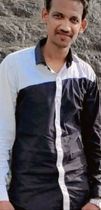 Man standing near a cascading waterfall on rocky landscape.