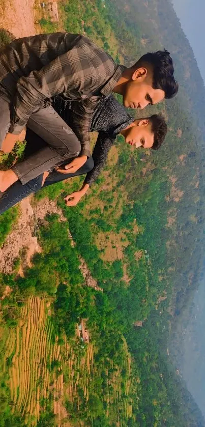 Mountain view with two friends sitting, overlooking green valleys.