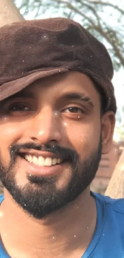 Smiling man in brown cap surrounded by trees.