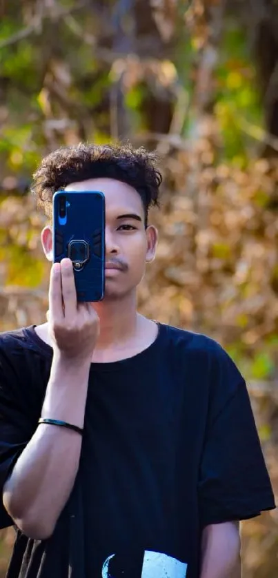 Young person holding phone with nature background.